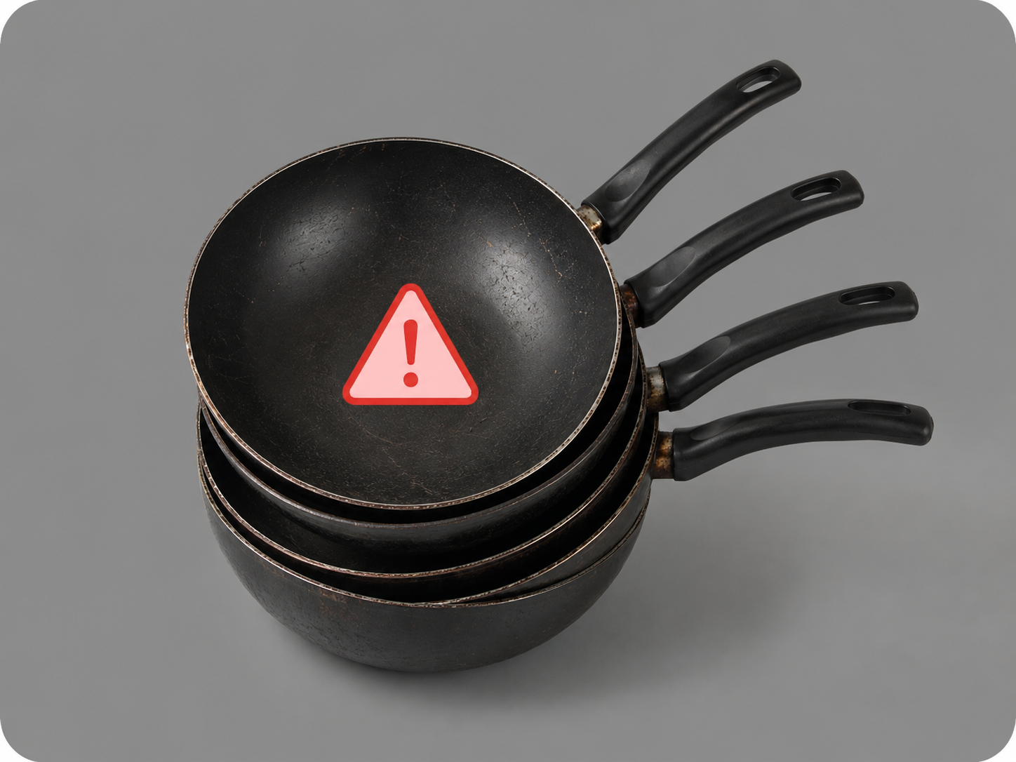 Quatre anciens woks à revêtement empilés avec pictogramme d'alerte